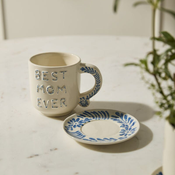 Mug with 'Best Mom Ever' text on a marble surface with a plant in the background