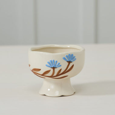 Small ceramic bowl with floral design on a white surface and light gray background