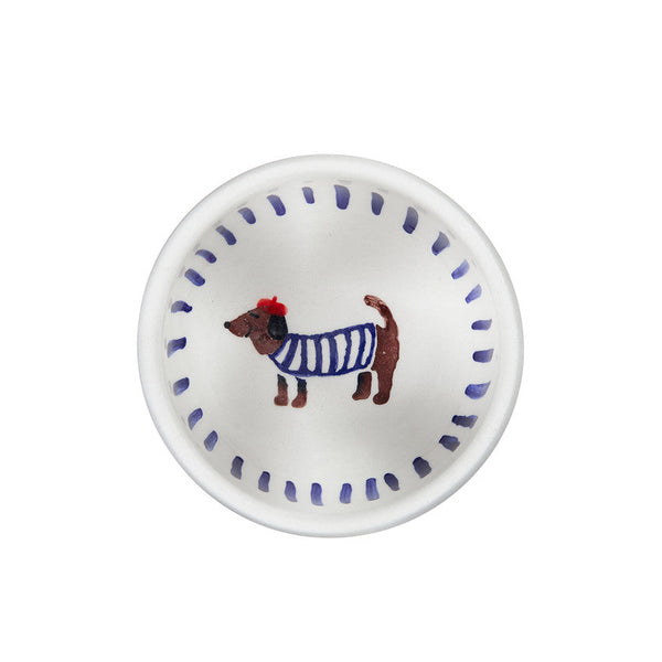 Small white plate with a dog illustration wearing a blue sweater on a white background