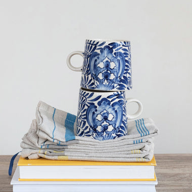 Stack of books with a stack of blue and white patterned towels on top, against a plain background.