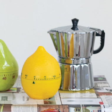 Decorative kitchen timers shaped like a strawberry on top of cookbooks.