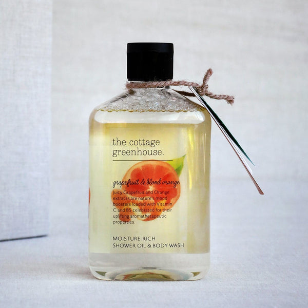 Bottle of 'The Cottage Greenhouse' shower oil and body wash on a light background
